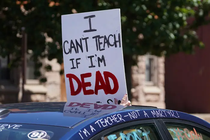 A sign that says "Can't Teach Them If I'm Dead"